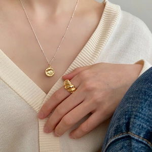 Minimalist 925 silver necklace with textured gold round pendant and ribbed ring on model