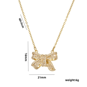 Gold bow necklace with clear crystals and dimensions of 16x21mm on white background