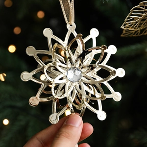 Golden metal snowflake ornament with central crystal on Christmas tree background