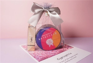 Detail of purple organza gift bag with silver bow, pearl charm, and cosmetic items