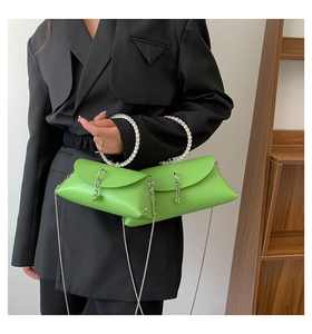 Detail of bright green jelly handbag with round handle and silver chain on a black suit