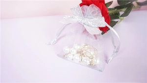 Close-up of a white organza drawstring pouch with a silver bow for jewelry storage