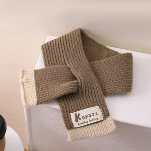 Detailansicht des Strickschals mit KUKUJI Lucky baby-Label auf einer Steinoberfläche