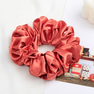 Detail of rose gold satin scrunchie with bubble candle on aesthetic white background