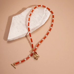 Detail of maple leaf pendant necklace with red and white beads and gold OT toggle clasp