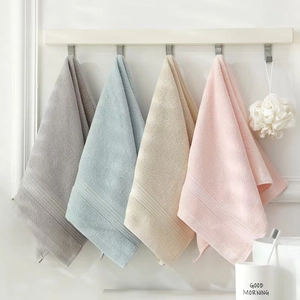 Four thick cotton towels in grey, blue, beige, and pink hanging on hooks for a cozy bathroom