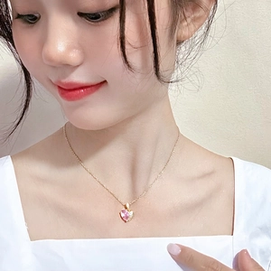 Détail du collier en pierre rose en forme de cœur sur un modèle avec chaîne dorée