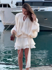 Detailed view of white pleated chiffon mini dress with lantern sleeves and tiered ruffles