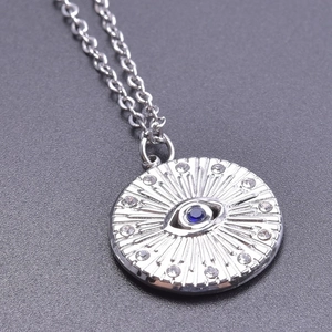 Macro shot of silver evil eye necklace pendant with blue gemstone and clear crystals