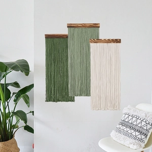 Set di tre arazzi da parete in macramè boho verde e beige su una parete bianca