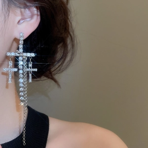 Macro shot of sparkling silver cross earrings with multi-layered tassel chains
