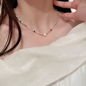 Gros plan d'un collier à chaîne fine orné de perles colorées et d'un pendentif marguerite