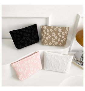 Detail of four floral embossed cosmetic bags in black, beige, pink and white colors