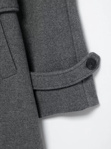 Detailed close-up of dark grey wool coat sleeve featuring belted cuff and black button