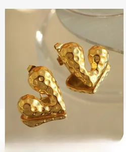 Close-up of golden heart earrings with hammer-textured finish and luxury metallic luster