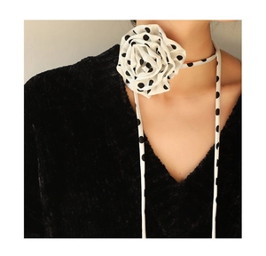 Detail of a large black and white polka dot chiffon rose flower choker with long ribbons