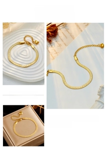 Close-up of 18K gold snake chain bracelet featuring heart pendant and lobster clasp