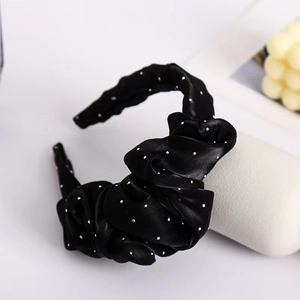 Close-up of black pleated headband with sparkling rhinestones and mesh flower detail
