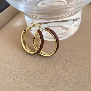 Minimalist gold circle earrings with brown velvet inlay in a warm lifestyle setting