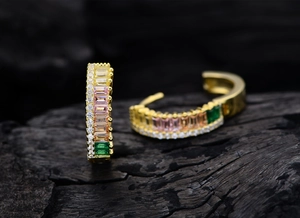 Macro detail of gold-plated silver earrings with colorful trapezoid cut zircons