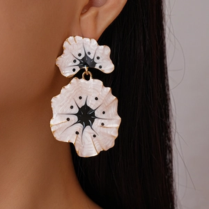 Detailed close-up of pink enamel ginkgo flower earrings with gold edges on model