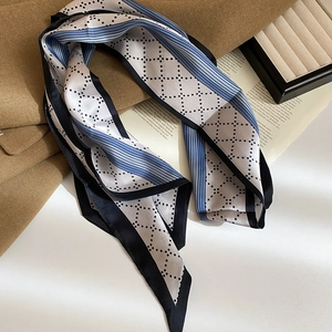 Detail of elegant blue and white silk scarf with geometric diamond pattern on coat
