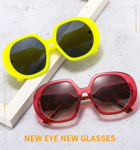 Detail view of oversized geometric sunglasses in vibrant yellow and burgundy plastic frames