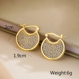 Gros plan de boucles d'oreilles géométriques dorées avec zircons et mesures de taille