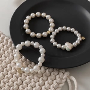 Detailed shot of pearl bracelets with gold charms and heart bead on a black tray