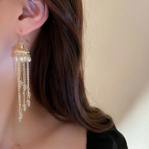 Macro shot of long gold tassel earrings with clear crystals on model for a luxury look