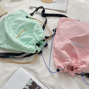 Detail of mint green and pink drawstring backpacks with delicate embroidery and nylon texture