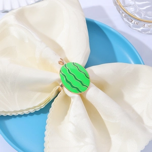 Macro shot of watermelon-shaped metal napkin ring with green enamel and golden details