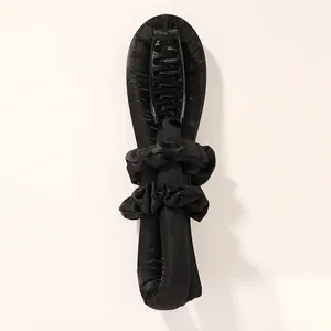 Detail of black heatless hair curler set with satin roller, claw clip, and scrunchies
