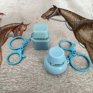 Detail view of square and round blue clicker fidget keychains on textured fabric