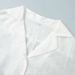 Dettaglio del colletto di una camicia bianca strutturata con revers ed etichetta S