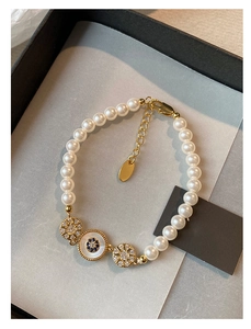 Détail d'un bracelet en perles plaqué or 18 carats avec breloques en zircon