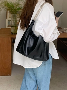 Close-up of black PU leather hobo bag with silver chain strap on a model shoulder