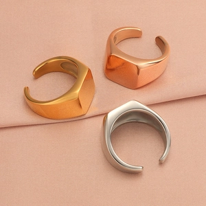 Three geometric square open rings in gold, rose gold, and silver finishes on soft fabric