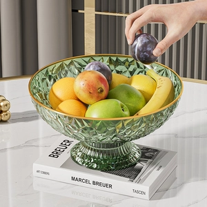 Detail of green glass fruit bowl with gold rim on art books in a modern luxury setting