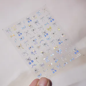 Close-up of blue bow nail art stickers with crystal rhinestones and holographic finish