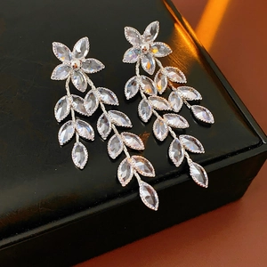 Close-up of silver leaf drop earrings with sparkling crystals on a black leather jewelry box