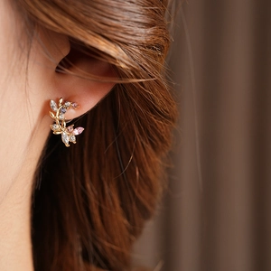 Detailed close-up of vintage branch earrings with colorful stones on a model ear