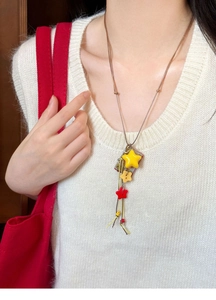 Detail of colorful star acrylic charms on a long cord necklace worn with a knit vest