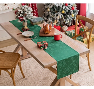 Festive green Christmas table runner with snowflake jacquard pattern on a wooden table
