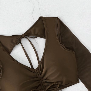 Detail view of dark brown V-neck swimwear with ruched texture and delicate tie straps