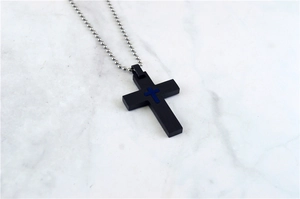 Macro detail of punk cross pendant in black and blue on silver bead chain necklace