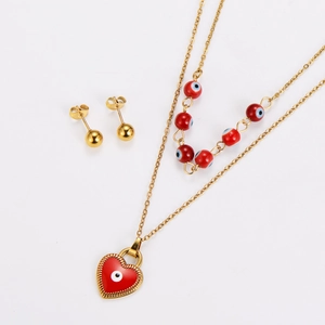 Flat lay of gold devil's eye necklace set with red heart pendant and bead earrings