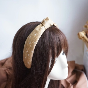 Detail shot of beige raffia woven headband with white polka dots and stylish top knot