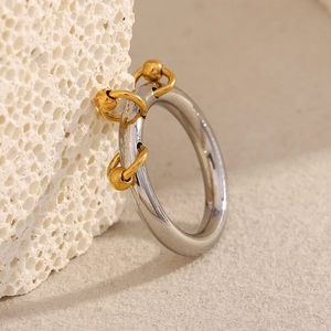 Detail view of silver ring with three gold bead pendants on textured white stone background