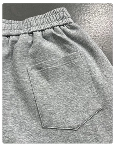 Detail of grey knitted trousers featuring elastic waistband and rear patch pocket